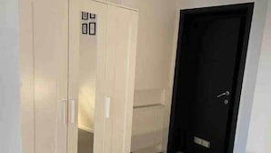 A room with a white wardrobe, a black door, and tiled flooring.
