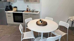 A modern kitchen with white cabinetry, a dining table with white chairs, and a small white table with a chair.