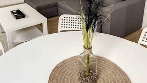 A modern living room with a grey sofa, a white coffee table, and a round table with a woven placemat.