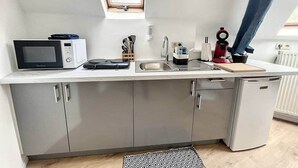 A compact kitchen with a microwave, sink, and a small refrigerator.