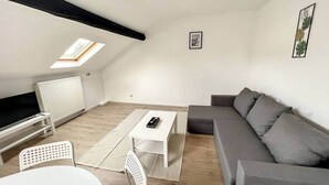 A modern living room with a sofa, a coffee table, a TV, and a skylight.
