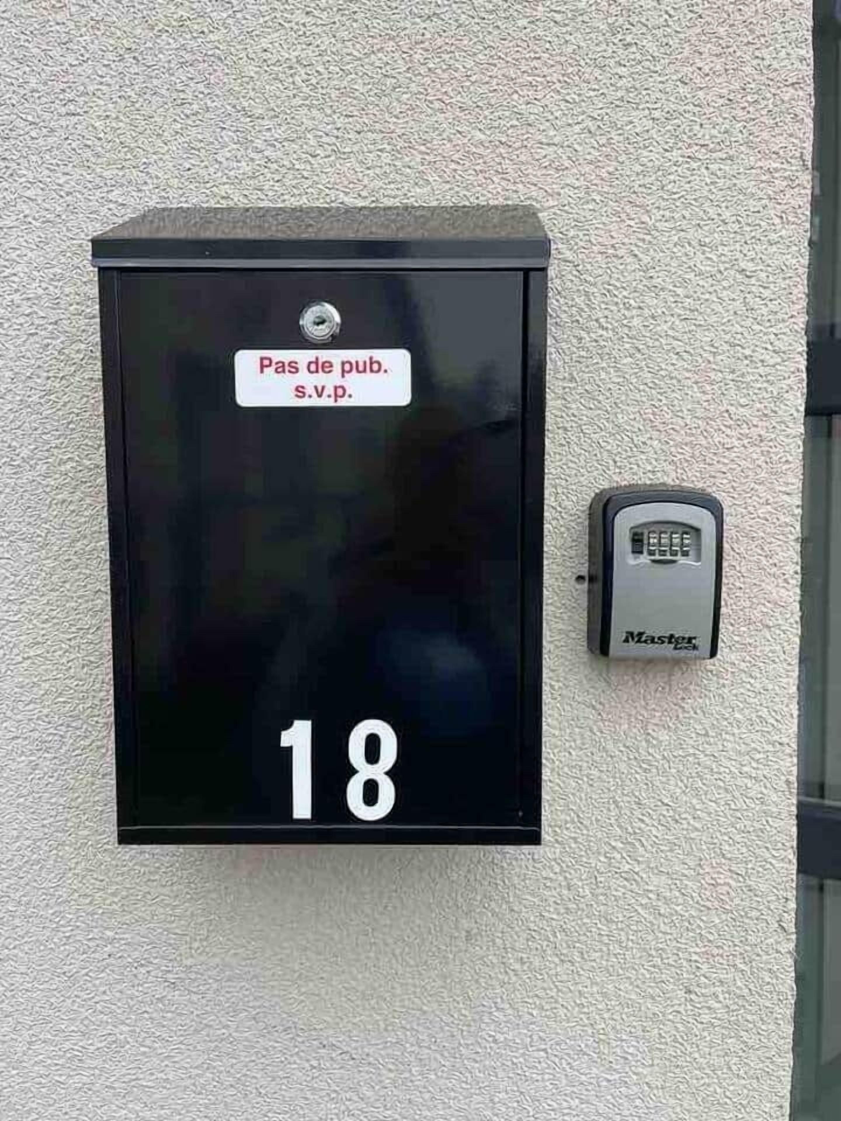 A black mailbox with a label indicating 'Pas de pub. s.v.p.' and the number 18.