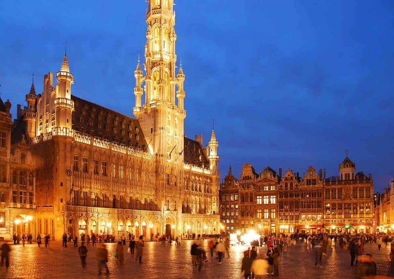 Ein historisches Gebäude mit aufwendiger Architektur, einem markanten Turm und einem belebten Platz.