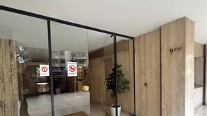 A modern interior with a glass door entrance, a potted plant, and a marble floor. - Panoramic Paris Views - 3BR Near Eiffel Tower & Seine (Boulogne-Billancourt)