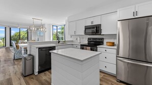 A modern kitchen with white cabinetry, stainless steel appliances, and a large island.