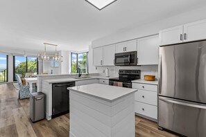 Una cocina moderna con armarios blancos, electrodomésticos de acero inoxidable y una isla grande.