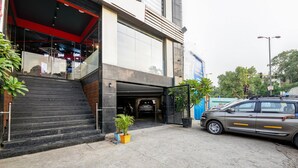 Ein Gebäudeeingang mit einer Treppe, die zu einer Glastür führt, ein geparktes Auto und ein Blumentopf.