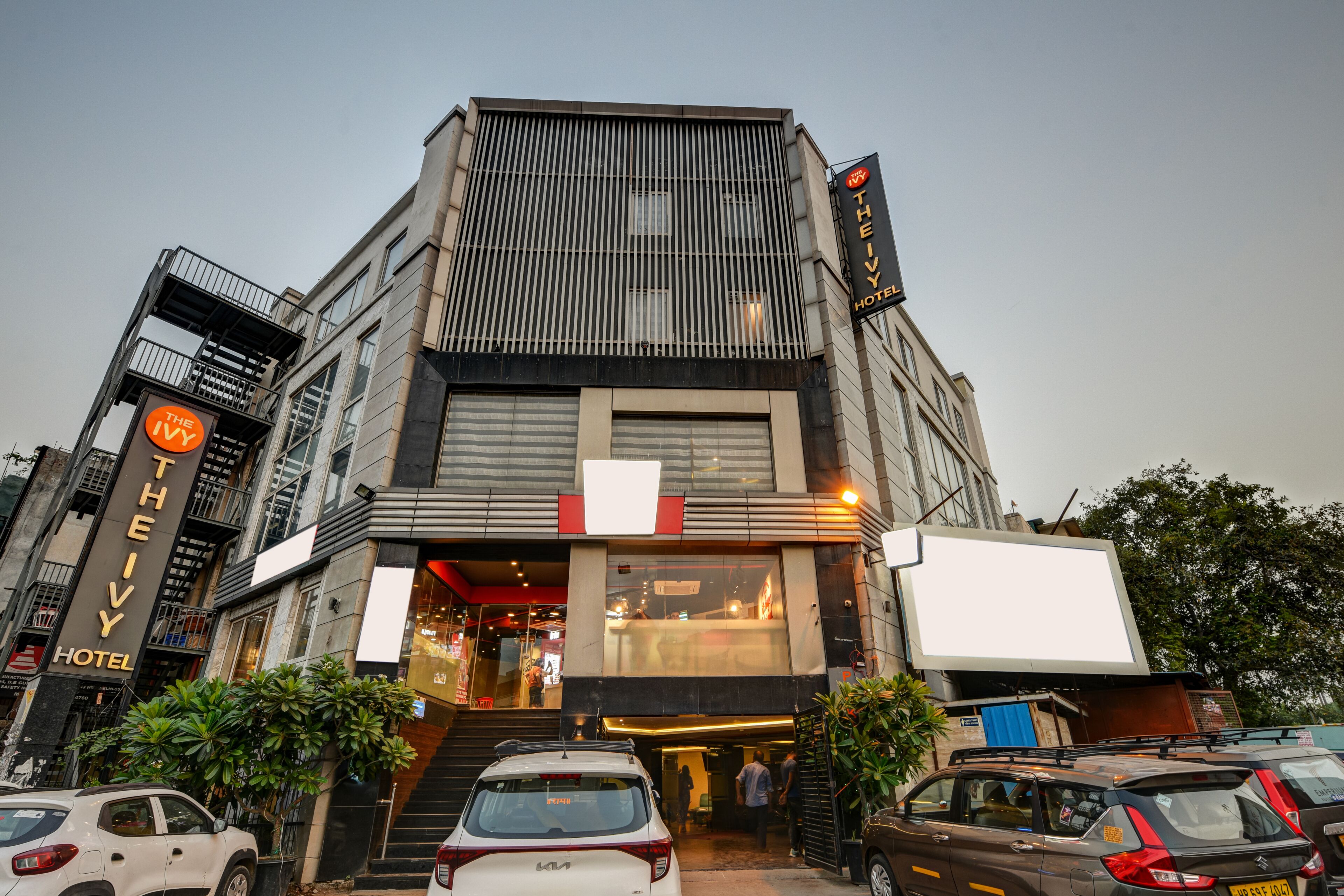 A hotel with a modern facade, a visible entrance, and a parking area with cars.