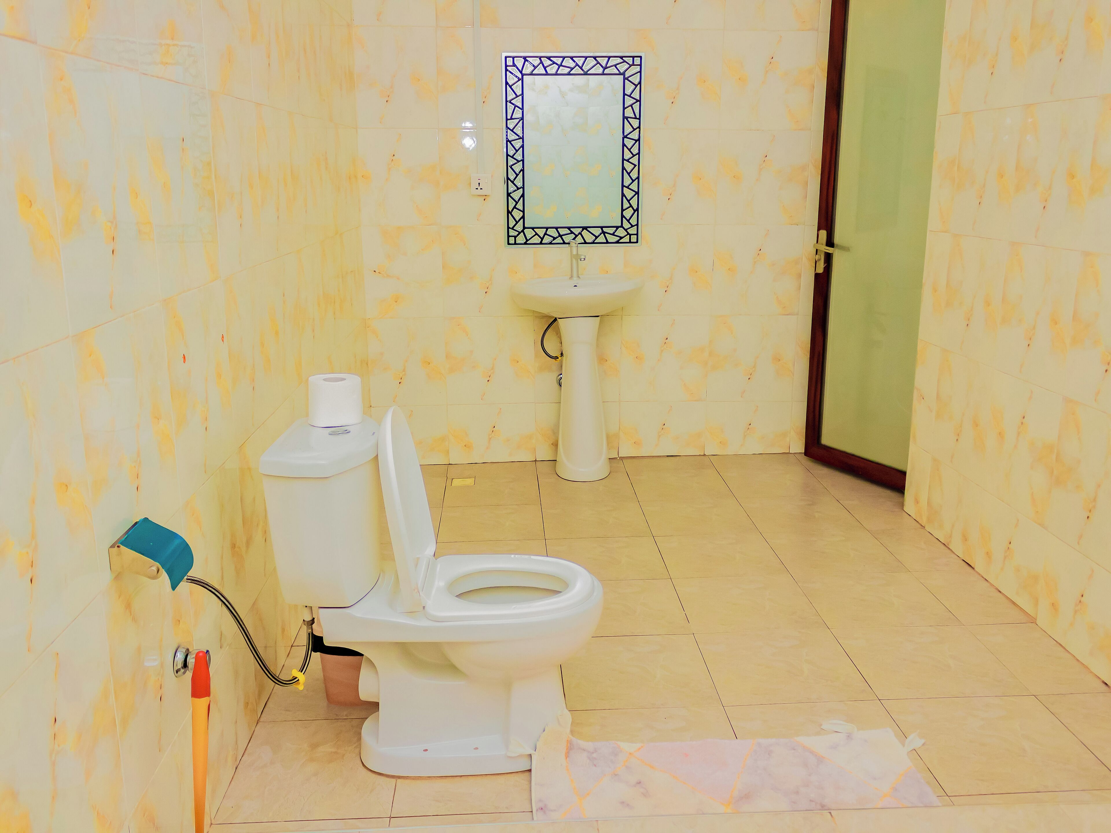A bathroom with a toilet, sink, and mirror.