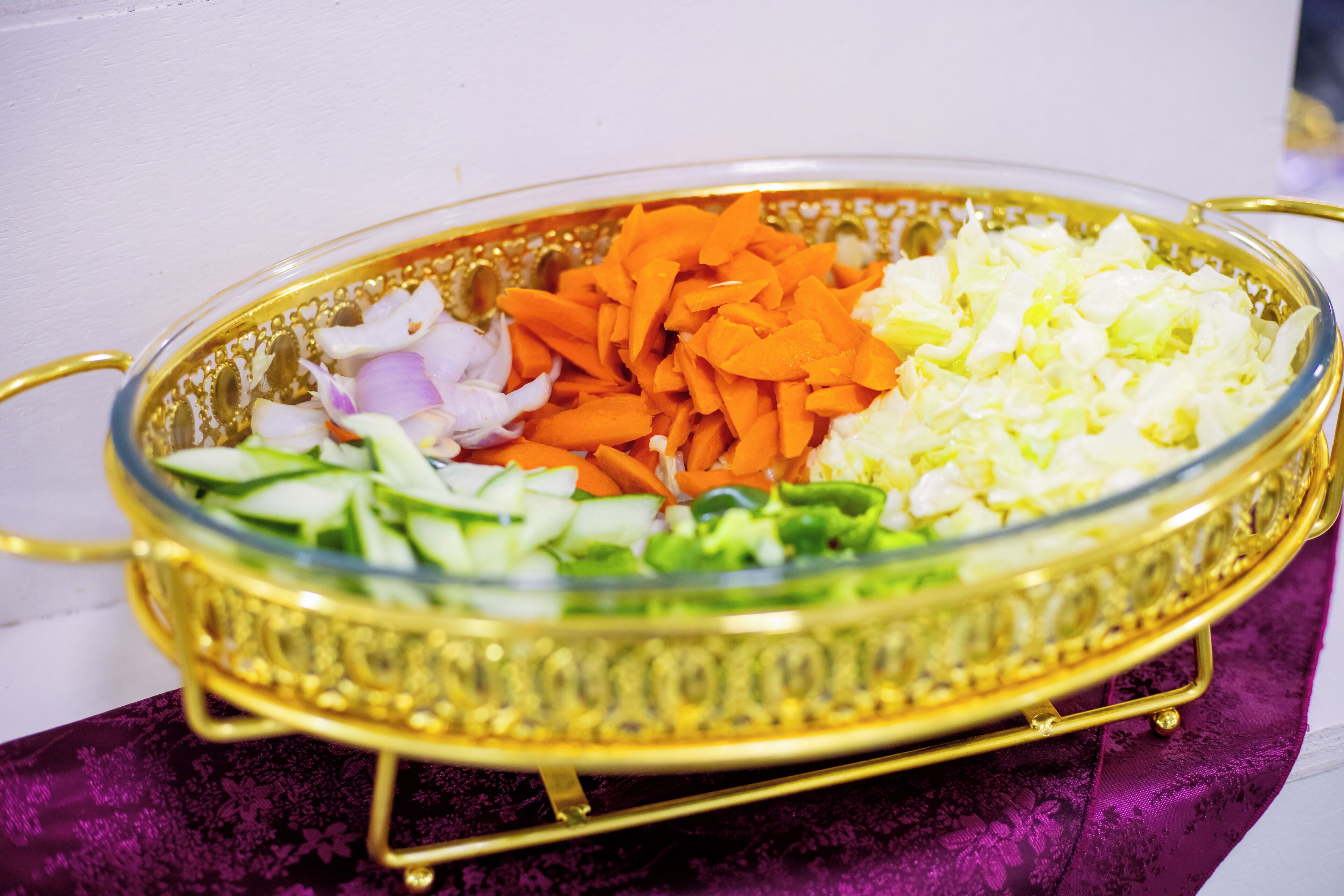 A glass bowl with a gold rim containing chopped vegetables.