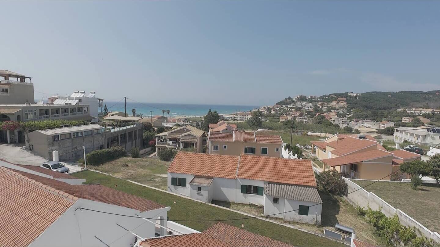 A residential area with houses, a clear sky, and a view of the sea.