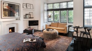 A modern living room with a large bed, a fireplace, a sofa, a coffee table, and a TV.