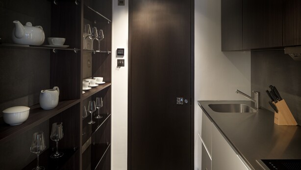 A modern kitchen with dark cabinetry, a stainless steel sink, and a knife block. - Luxury Suite in Cadogan Square 1 (London)
