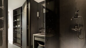 A modern bathroom with a glass-enclosed shower, a built-in vanity, and a dark-toned shelving unit with glassware. - Luxury Suite in Cadogan Square 1 (London)