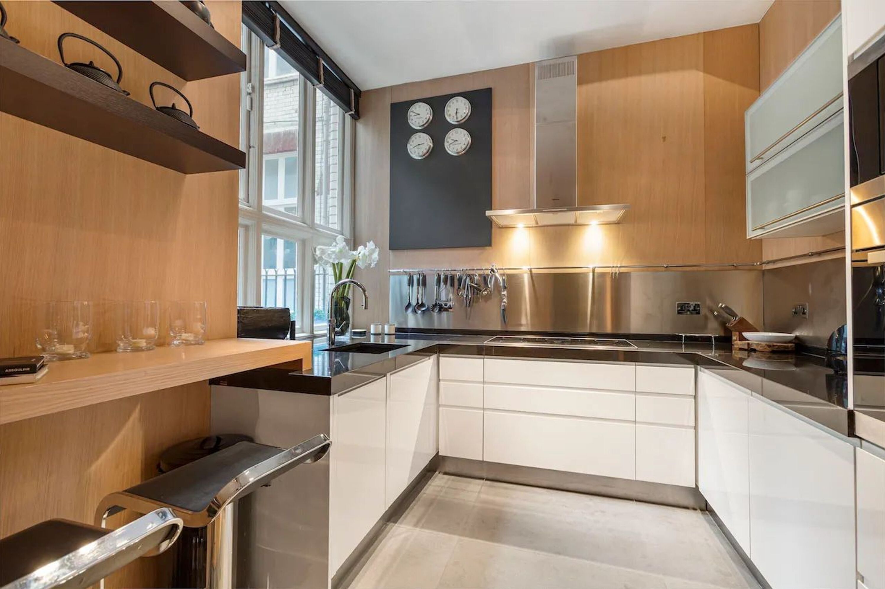 Una cocina moderna con armarios de madera, electrodomésticos de acero inoxidable y un ventanal que proporciona luz natural.