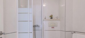 A modern bathroom with a glass shower enclosure, a toilet, and a sink with a towel rack.