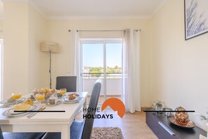 A dining area with a table set for breakfast, a view of the outdoors through a large window, and a modern interior design.