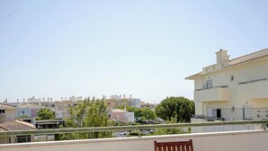 A balcony with a table and chairs, overlooking a residential area with multiple buildings. - #320 Family Apartment in the City Center (Albufeira)