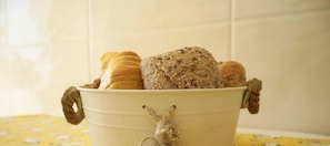 A metal bucket filled with various breads and a decorative keychain.