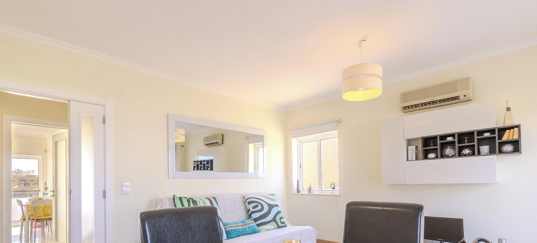 A dining area with a table set for breakfast, a sofa, and a TV stand with decorative items.