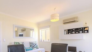 A dining area with a table set for breakfast, a sofa, and a TV stand with decorative items. - #320 Family Apartment in the City Center (Albufeira)