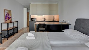 A modern hotel room with a neatly made bed, a small kitchenette, and a dining area. - RentPlanet - Studio Wałowa (Gdańsk)
