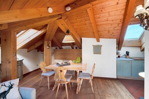 A wooden interior with a dining table, chairs, a kitchen area, and a skylight. - Apartment 'La Rocca' with Mountain View and Wi-Fi (Daiano)