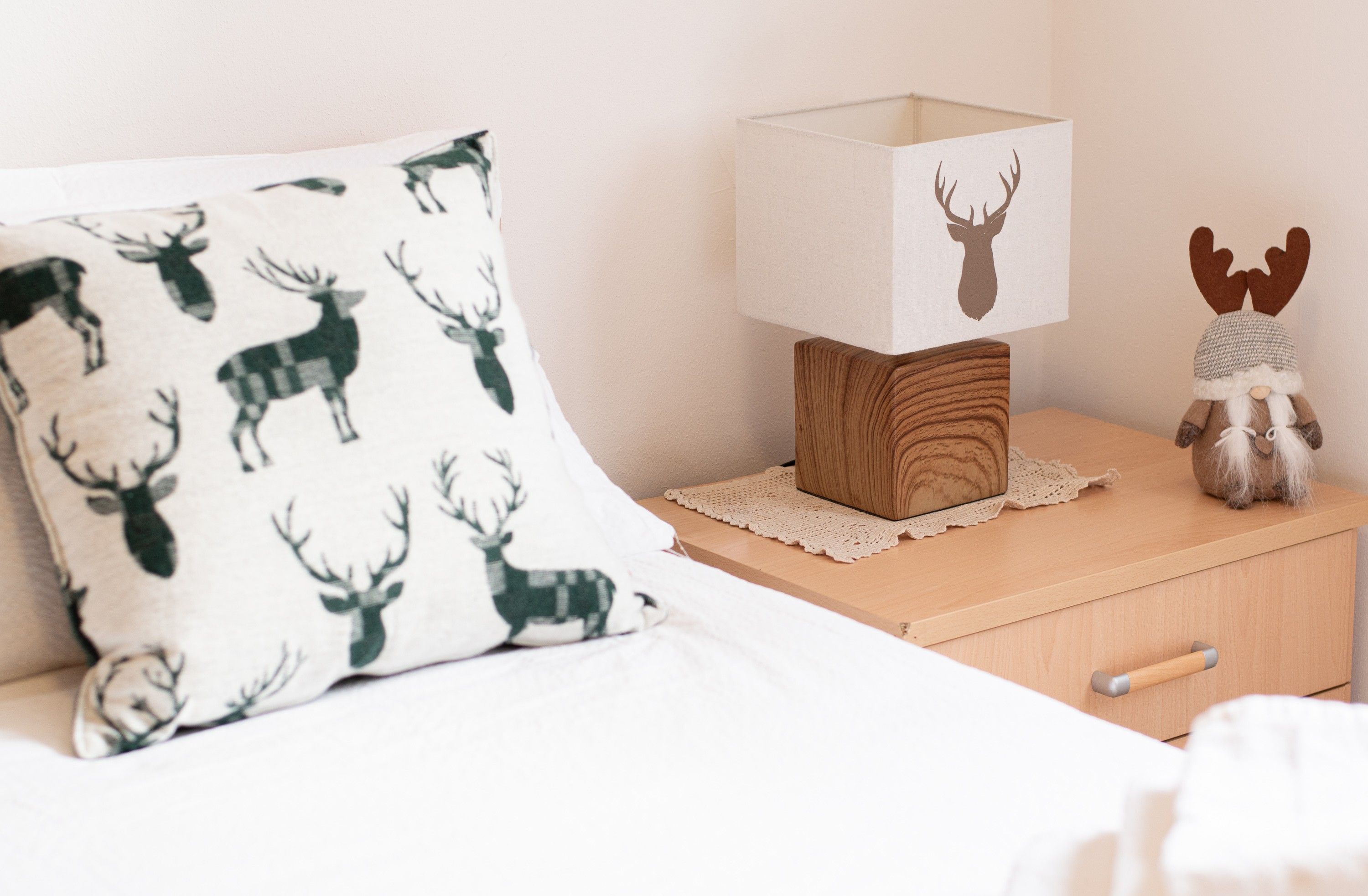 A bedroom with a bed, a nightstand, a lamp, a decorative pillow, and a plush toy.