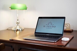 En MacBook Pro står på ett skrivbord i trä, tillsammans med en grön skrivbordslampa och ett guldfärgat stativ.