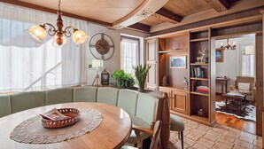 A dining area with a wooden table, green upholstered bench, and a chandelier. - Apartment 'Il Feudo' with Mountain View, Balcony and Wi-Fi (Predazzo)