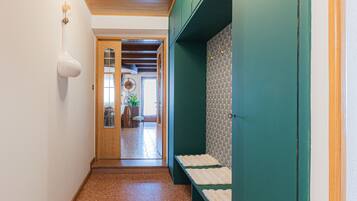 Ein Flur mit Holzboden, einer Tür zu einem anderen Raum und einer Wand in Grün mit einem gemusterten Design.