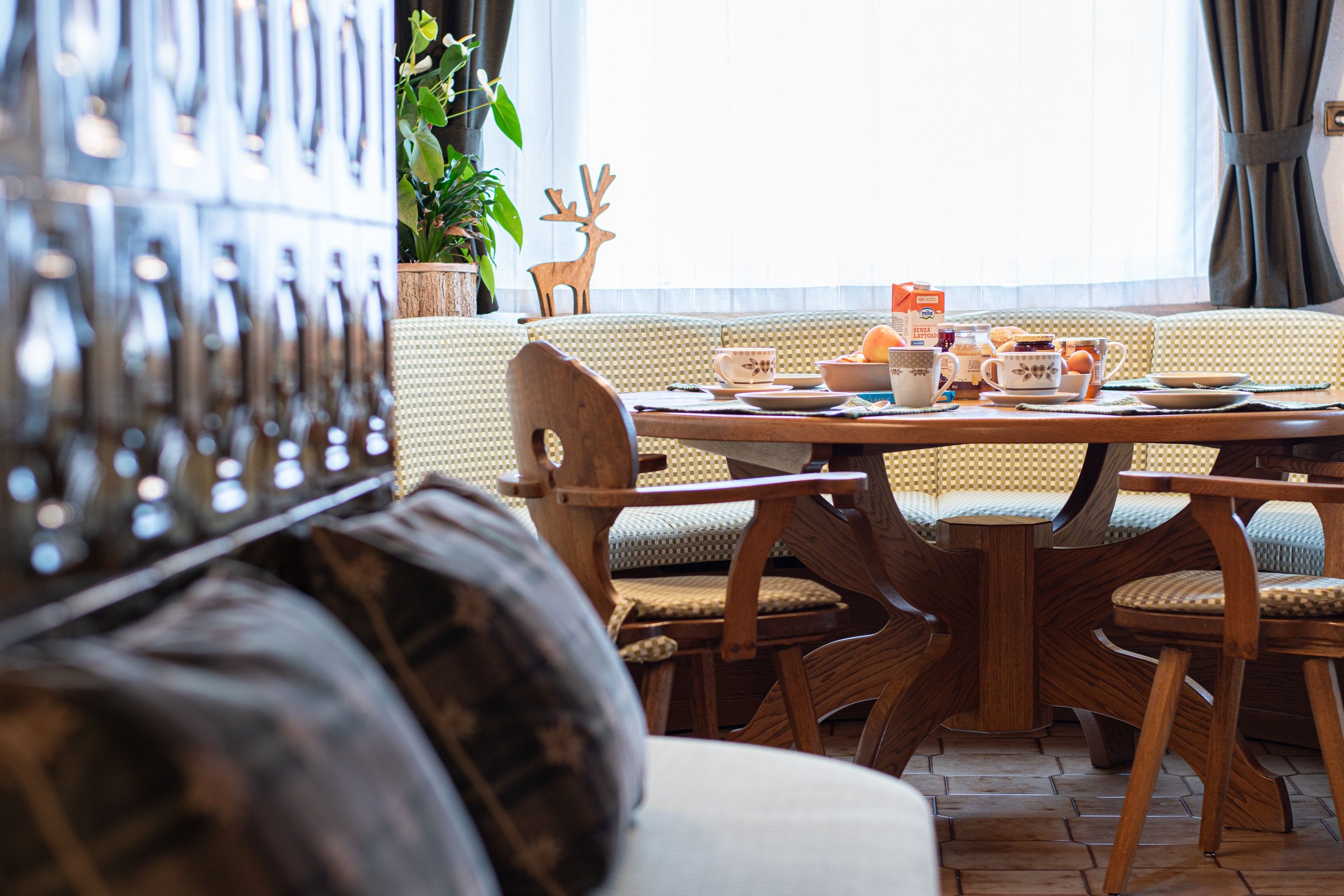 A cozy dining area with a round table, wooden chairs, and a checkered sofa.