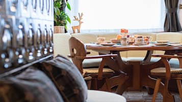 A cozy dining area with a round table, wooden chairs, and a checkered sofa.