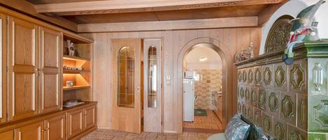 A room with wooden cabinets, a green upholstered bench, and a tiled floor.