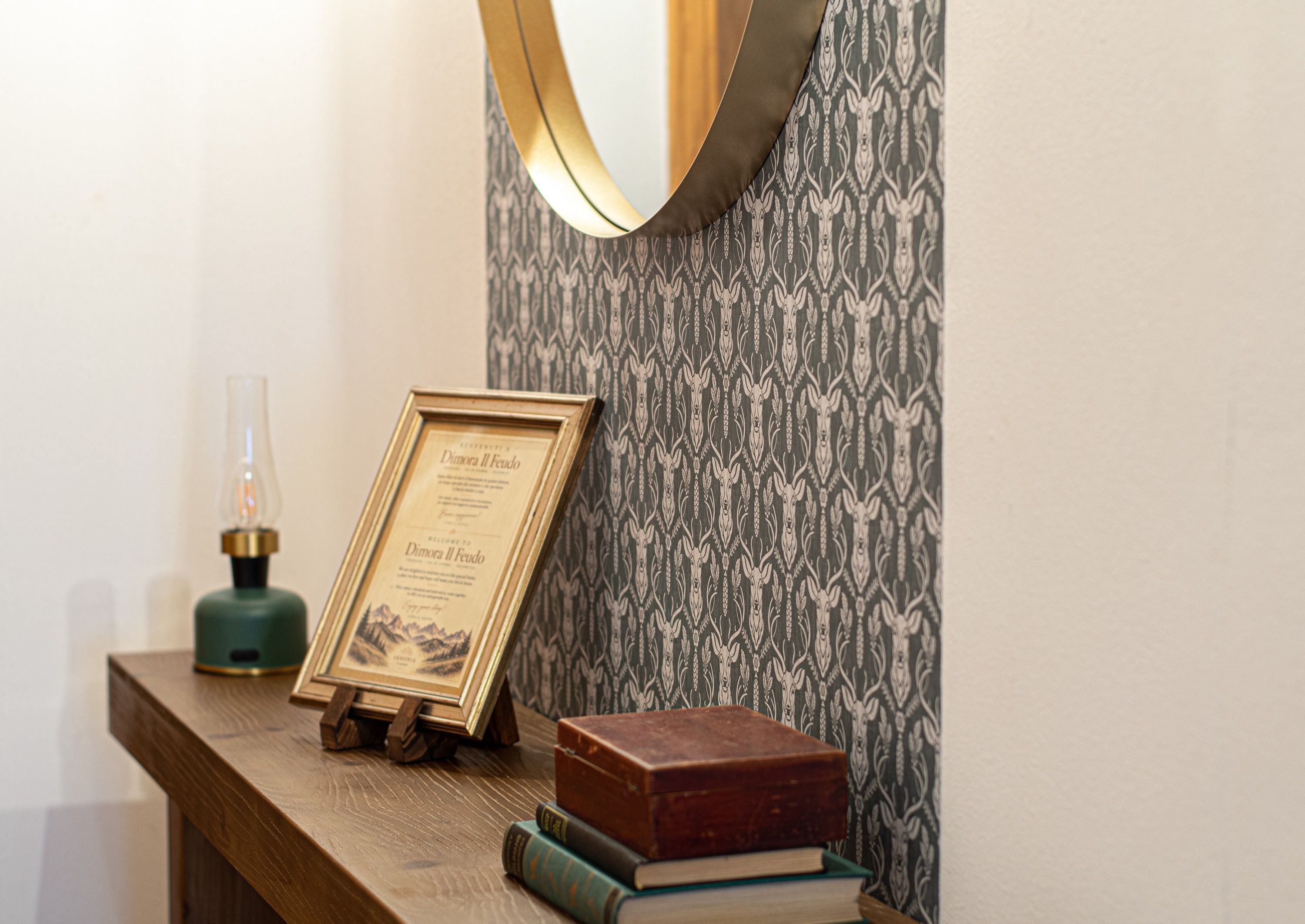 A framed certificate on a wooden stand, a green bottle, and a stack of books on a wooden surface.