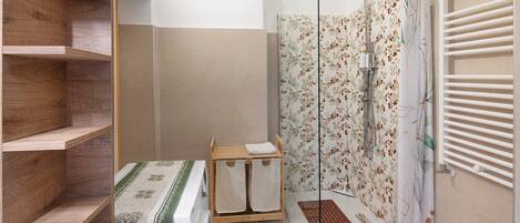 Een badkamer met een douche, een houten plankunit en een klein tafeltje met handdoeken.
