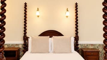 A bed with a wooden headboard, two bedside tables, and two wall-mounted lights.
