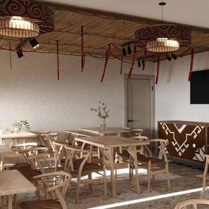 Une pièce avec des tables et des chaises en bois, une porte et un mur orné de motifs.