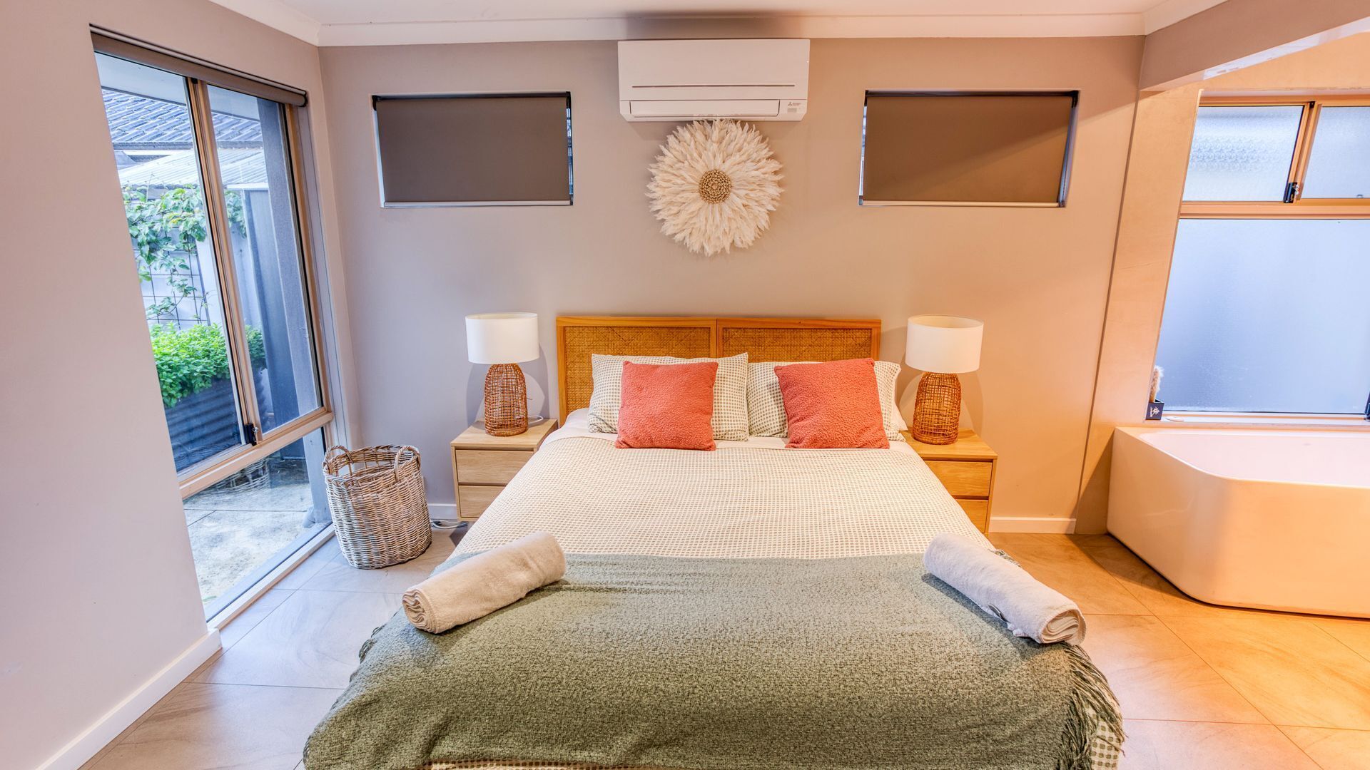 A bedroom with a large bed, two nightstands, a window, and a ceiling fan.
