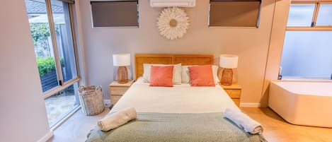 A bedroom with a large bed, two nightstands, a window, and a ceiling fan.