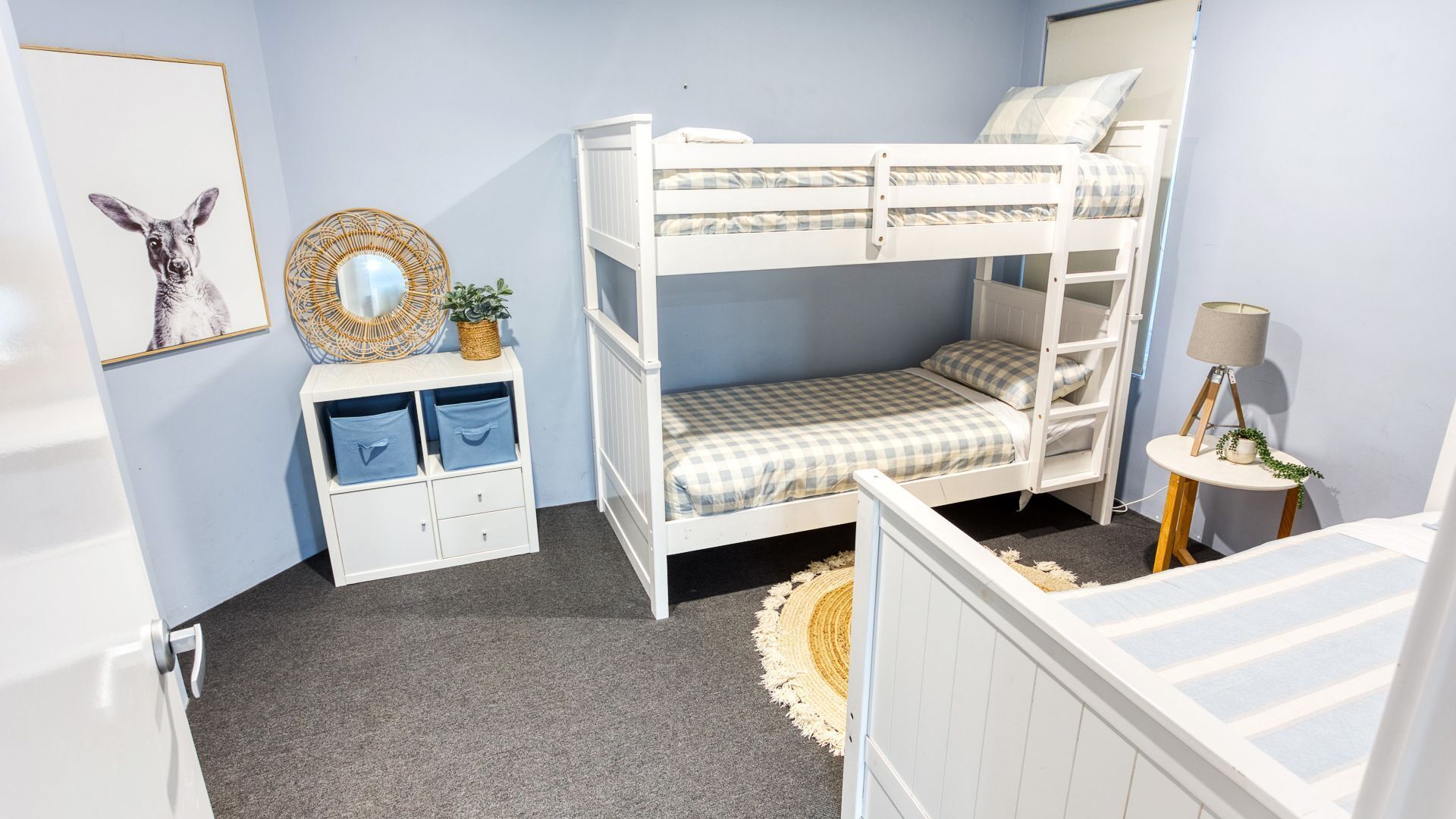 A bunk bed room with a small desk, a round mirror, and a lamp.