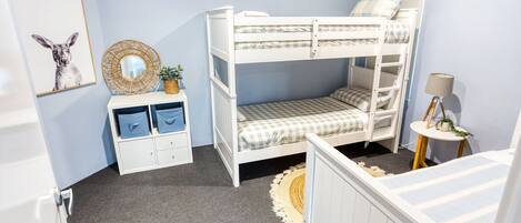 A bunk bed room with a small desk, a round mirror, and a lamp.