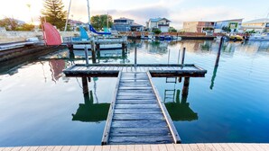 A wooden dock extending into calm water with boats docked nearby. - Aqua Tides – Stylish Waterfront Escape in Busselton (Geographe)