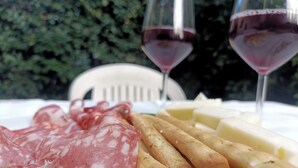 A table with various food items including cured meats and cheeses, accompanied by two glasses of red wine. - The key to time (Lucca)