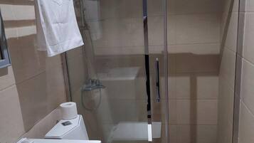 A modern bathroom with a glass-enclosed shower, a white sink, and a towel rack.
