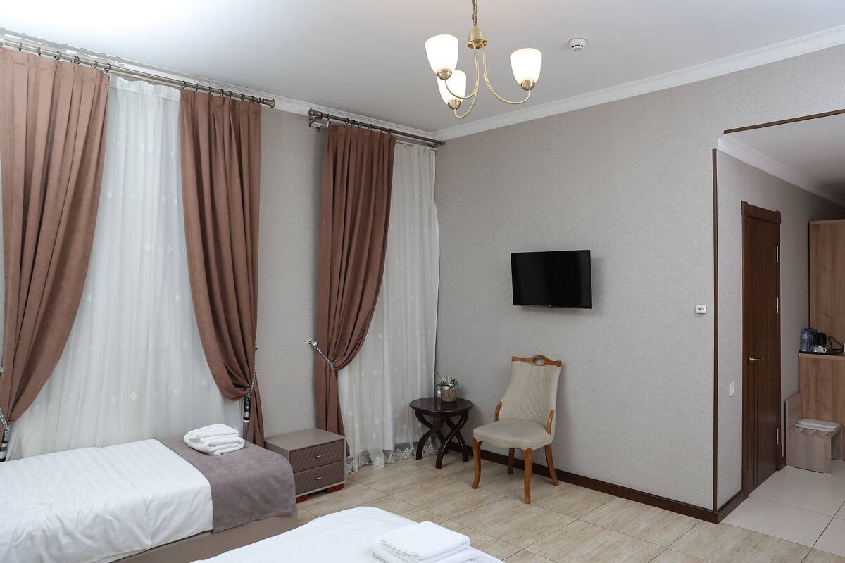 A hotel room with two beds, a TV, a chair, and a small table.