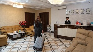 Uma área de recepção com recepcionista, balcão e espaço de espera com sofá e mesinha de centro.