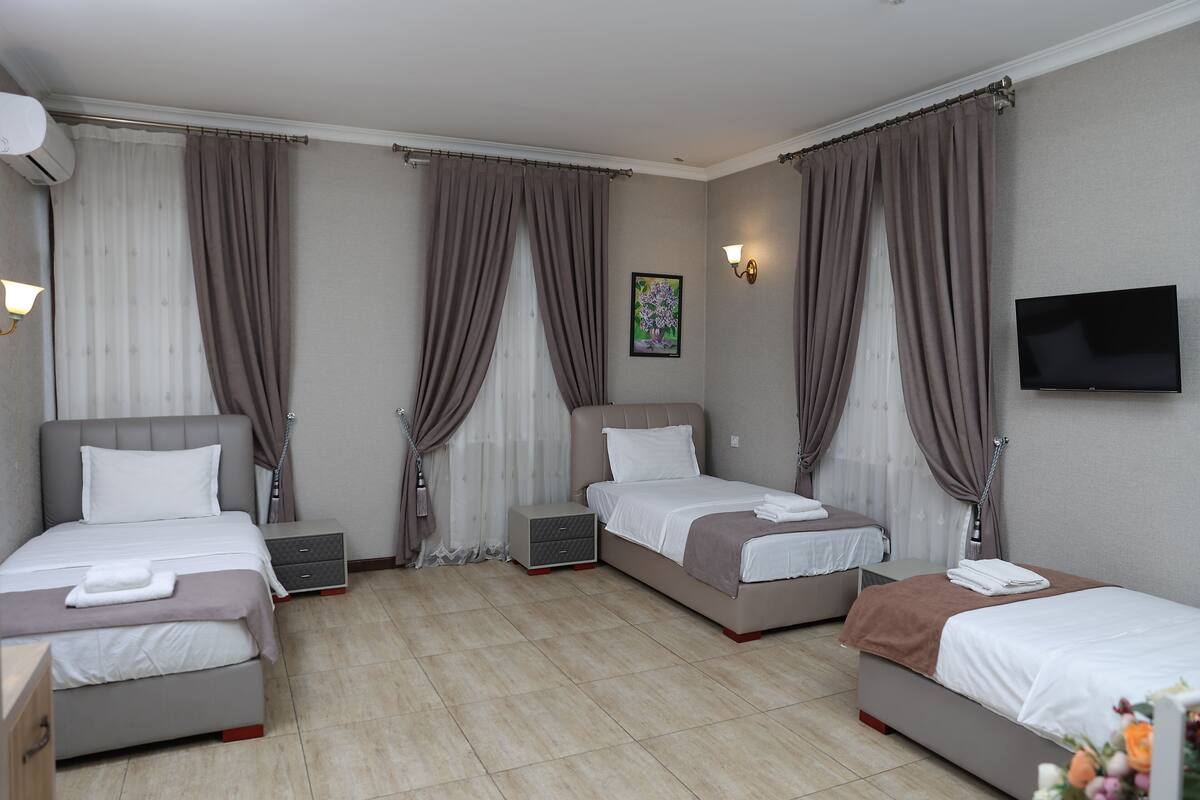 A hotel room with two beds, a TV, a bedside table, and a wall-mounted light.