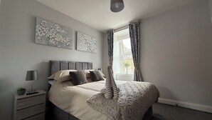A bedroom with a bed, a nightstand, a lamp, and two wall art pieces.