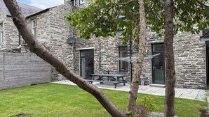 A stone building with a grassy yard, a hammock, and a picnic table.